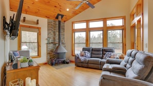 A cozy living room with a fireplace, leather sofa, and large windows. - Pet-friendly Hancock Home on the Delaware River! (Hancock)