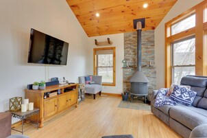 A cozy living room with a fireplace, a comfortable sofa, and a television mounted on the wall.