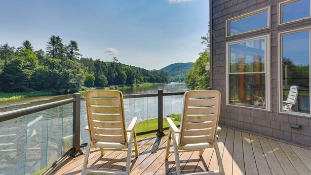 A wooden deck with two chairs overlooking a river and forested hills. - Pet-friendly Hancock Home on the Delaware River! (Hancock)