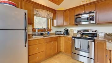 A kitchen with wooden cabinets, a stainless steel refrigerator, a microwave, a stove, and a toaster.