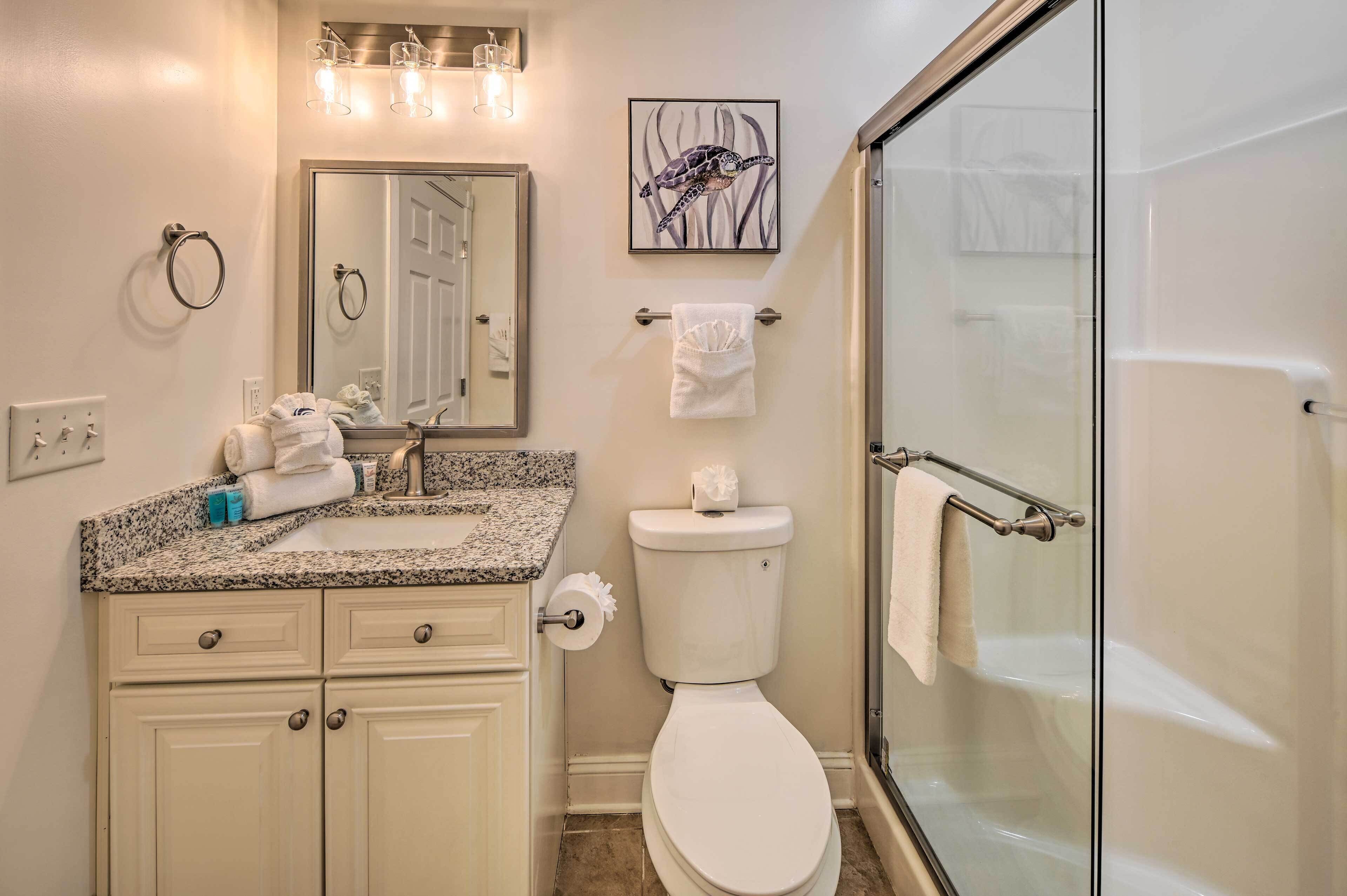 A bathroom with a sink, toilet, and glass shower enclosure.