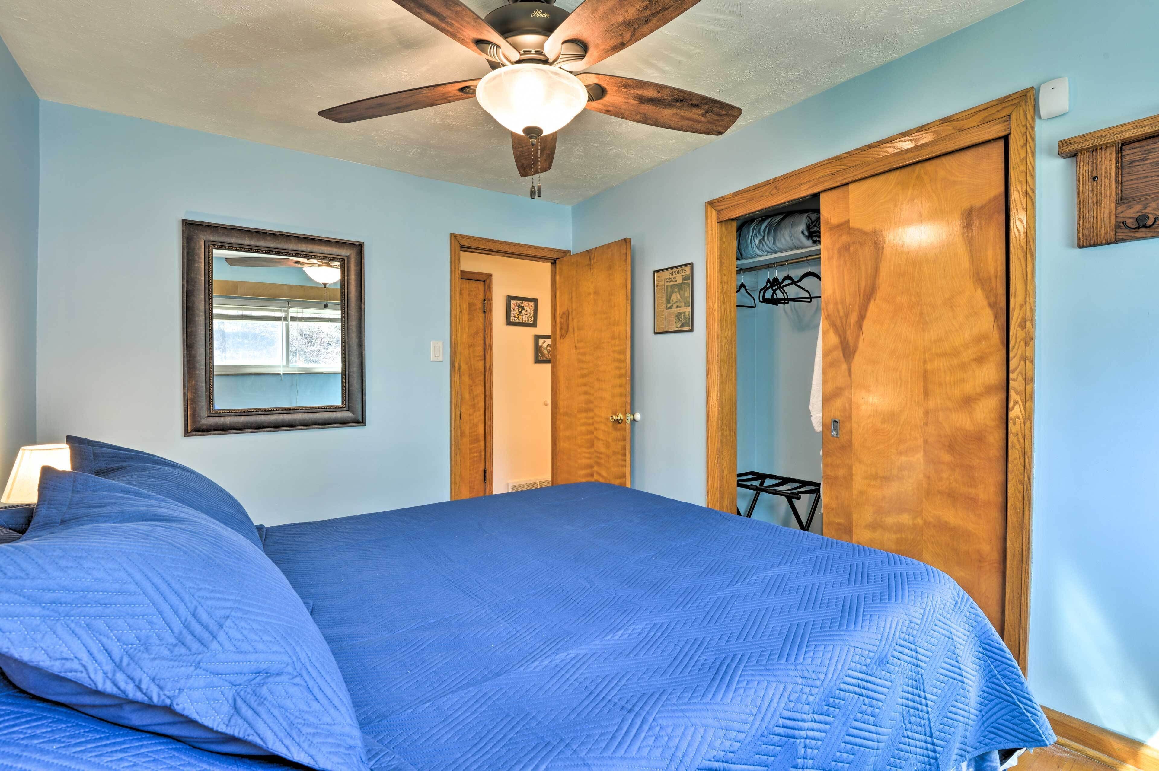Un dormitorio con cama, ventilador de techo, puertas de madera y armario.