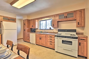 A kitchen with wooden cabinets, a refrigerator, a stove, and a window.