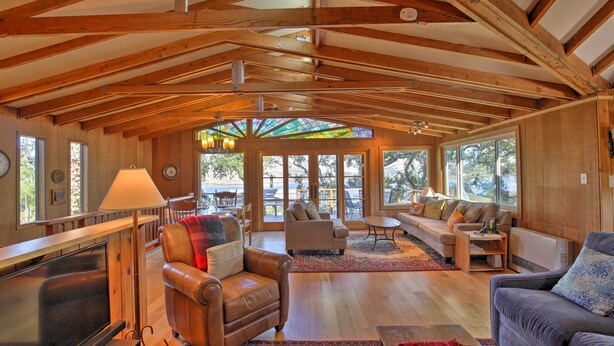 A spacious living room with wooden beams, large windows, and comfortable seating. - Hillside Home w/ Deck & Views of Tomales Bay! (Inverness)
