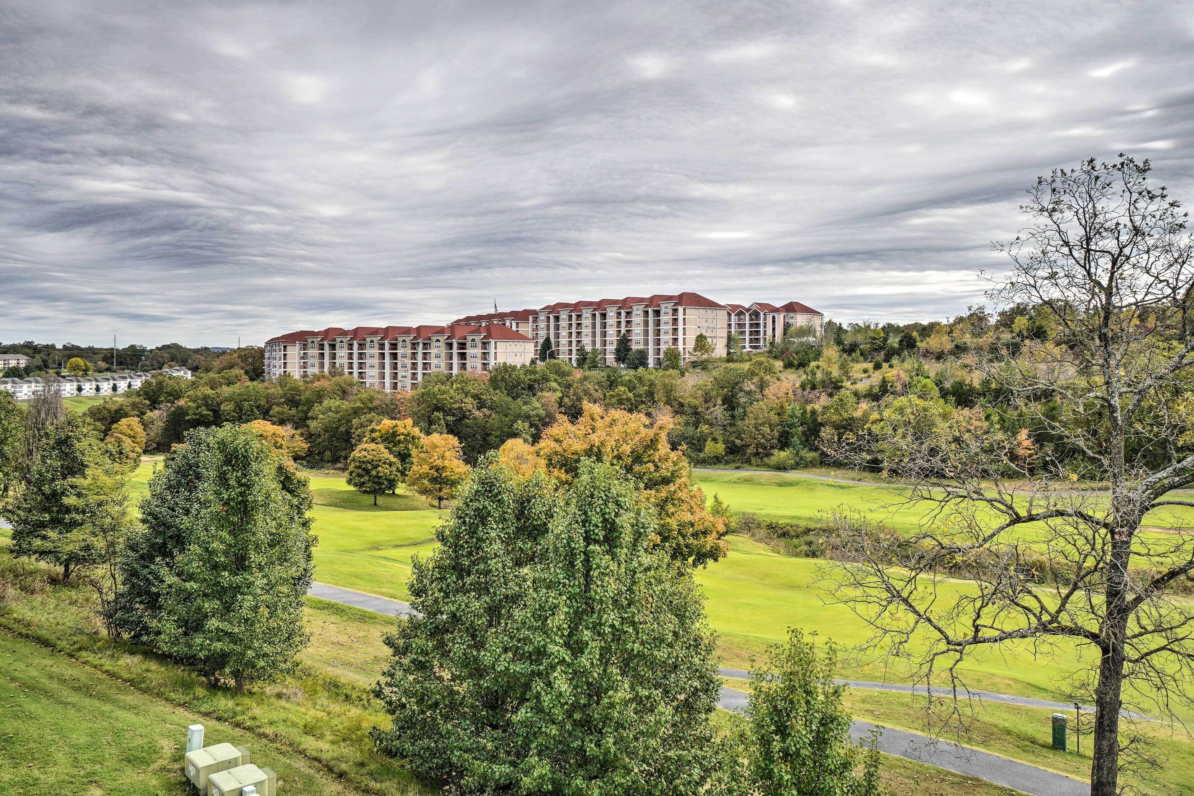 Un hotel grande con varios pisos y un techo rojo, rodeado de césped verde y árboles.