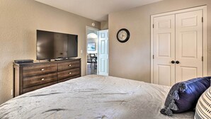 Une chambre à coucher comprenant un lit, une commode, un téléviseur, une horloge et une armoire.