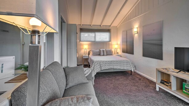 Un dormitorio moderno con sofá, dos camas, televisión y escritorio con computadora.