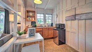 Una cocina con armarios de madera, una encimera blanca, un refrigerador negro y una lámpara colgante.