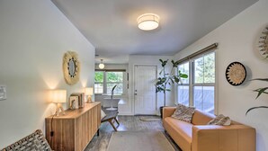 A living room with a wooden cabinet, a sofa, a coffee table, and a lamp. There is a door leading to another room, and a window with blinds. - San Diego Gem w/ Private Hot Tub, Close to Dtwn! (San Diego)