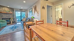 Un comedor con mesa y sillas de madera, una chimenea y vistas al exterior.