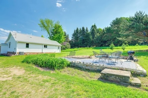 A white house with a patio area featuring outdoor furniture and a grill.