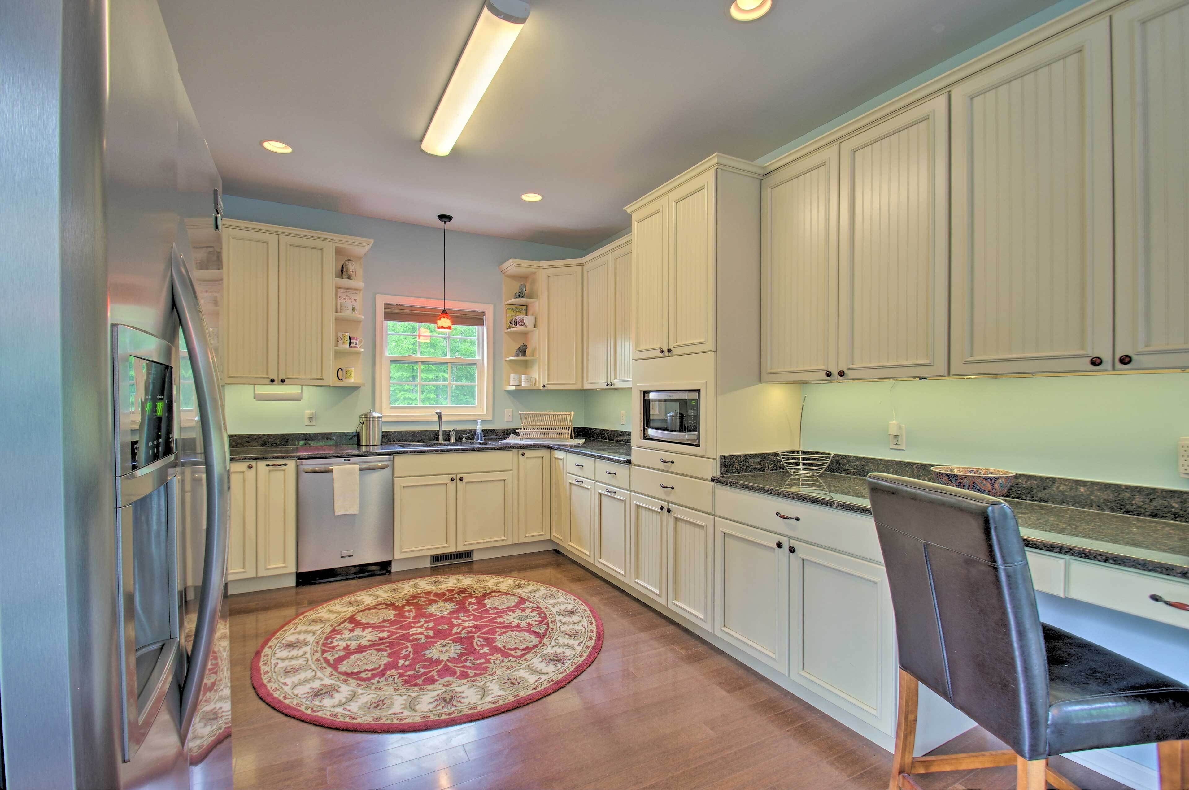 A modern kitchen with white cabinets, stainless steel appliances, and a red patterned rug.