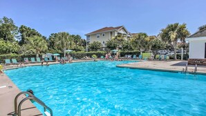 A swimming pool with clear blue water, surrounded by lounge chairs and umbrellas, with a building in the background. - Shuttle to Ocean! North Myrtle Beach Retreat (North Myrtle Beach)