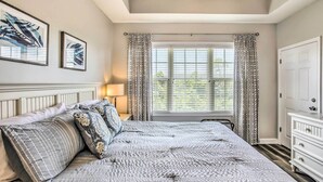 A bedroom with a large bed, a nightstand, a dresser, and a window with curtains. - Shuttle to Ocean! North Myrtle Beach Retreat (North Myrtle Beach)