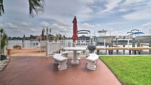 A marina with boats docked, a white table with two chairs, and a red umbrella.