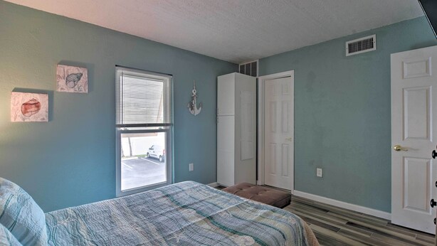 A bedroom with a bed, a window, a door, and a closet.
