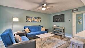 A living room with a blue sofa, a white coffee table, and a ceiling fan.