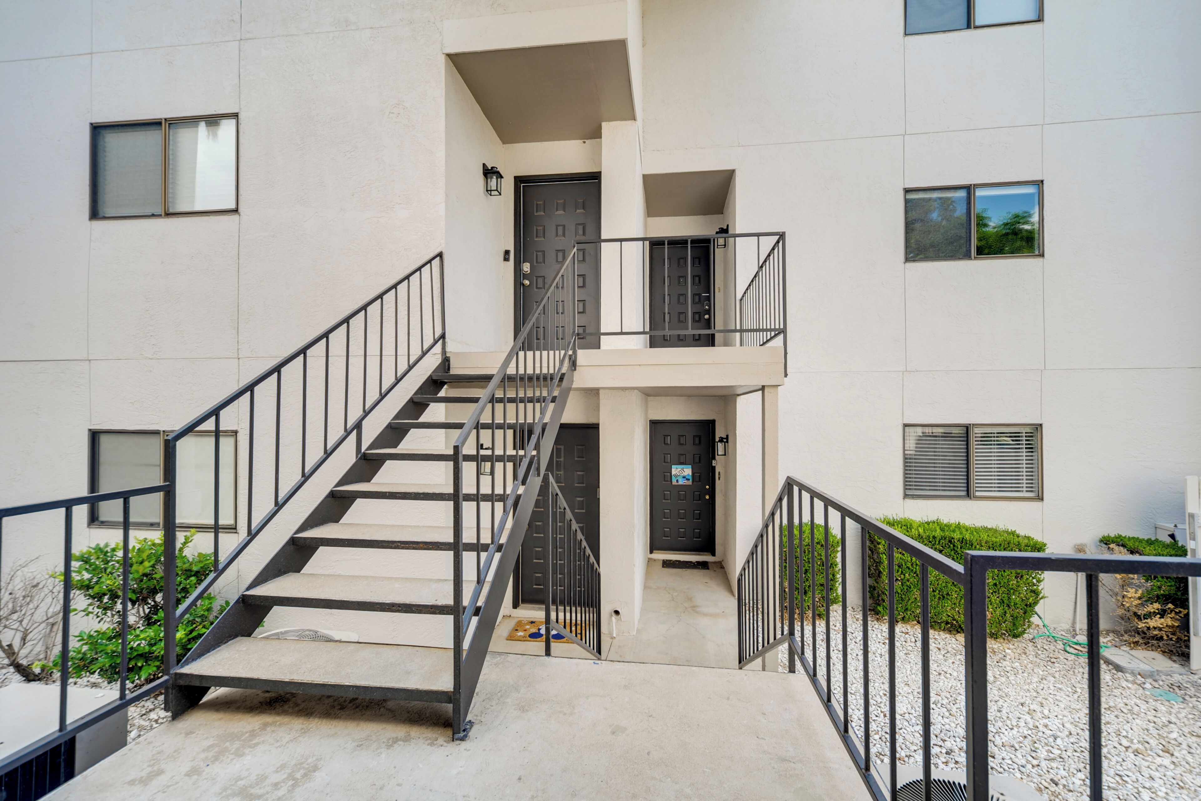 Un immeuble à plusieurs étages doté d’un escalier central, de portes extérieures et de fenêtres.