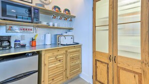 A compact kitchen with a microwave, toaster, coffee maker, and wooden cabinets. - Walk to Beach From Chic Old Town Apartment w/ Yard (Bay St Louis)