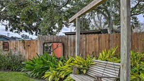 A wooden bench in a garden with a wooden fence and various plants. - Walk to Beach From Chic Old Town Apartment w/ Yard (Bay St Louis)