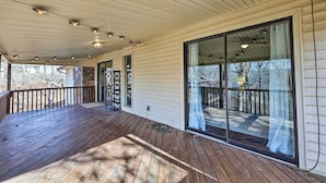 A covered porch with a wooden deck, large sliding glass doors, and string lights. - Spacious Bella Vista Home ~ 5 Mi to Lake! (Bella Vista)