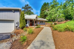 A single-story house with a front porch, a garage, and a well-maintained garden with various plants and flowers. - Hot Tub, Dock, Lakefront: Luxe Six Mile Retreat (Six Mile)