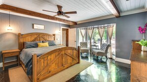 Une chambre avec un lit en bois, un ventilateur de plafond et une vue sur un patio extérieur.
