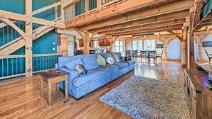 A spacious living area with a wooden staircase, a blue sofa, and a wooden coffee table.