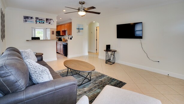 A modern living room with a leather sofa, a coffee table, and a flat-screen TV mounted on the wall. - 2 Mi to Bonita Beach: Bbq-ready Townhome! (Bonita Springs)