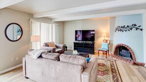 A living room with a sofa, TV, fireplace, and a mirror on the wall. - Pleasant Condo - 14 Mi to Dtwn Kansas City (Overland Park)