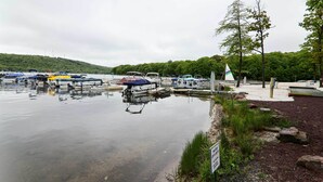 A marina with boats docked, a sign indicating water depth, and a forested hill in the background. - Near Skiing & Lakes: Contemporary Poconos Townhome (Lake Harmony)