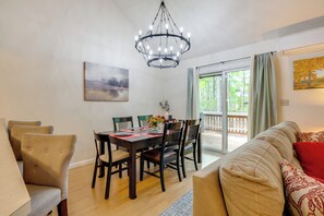 Un comedor con una mesa y sillas de madera, una araña y un cuadro en la pared.