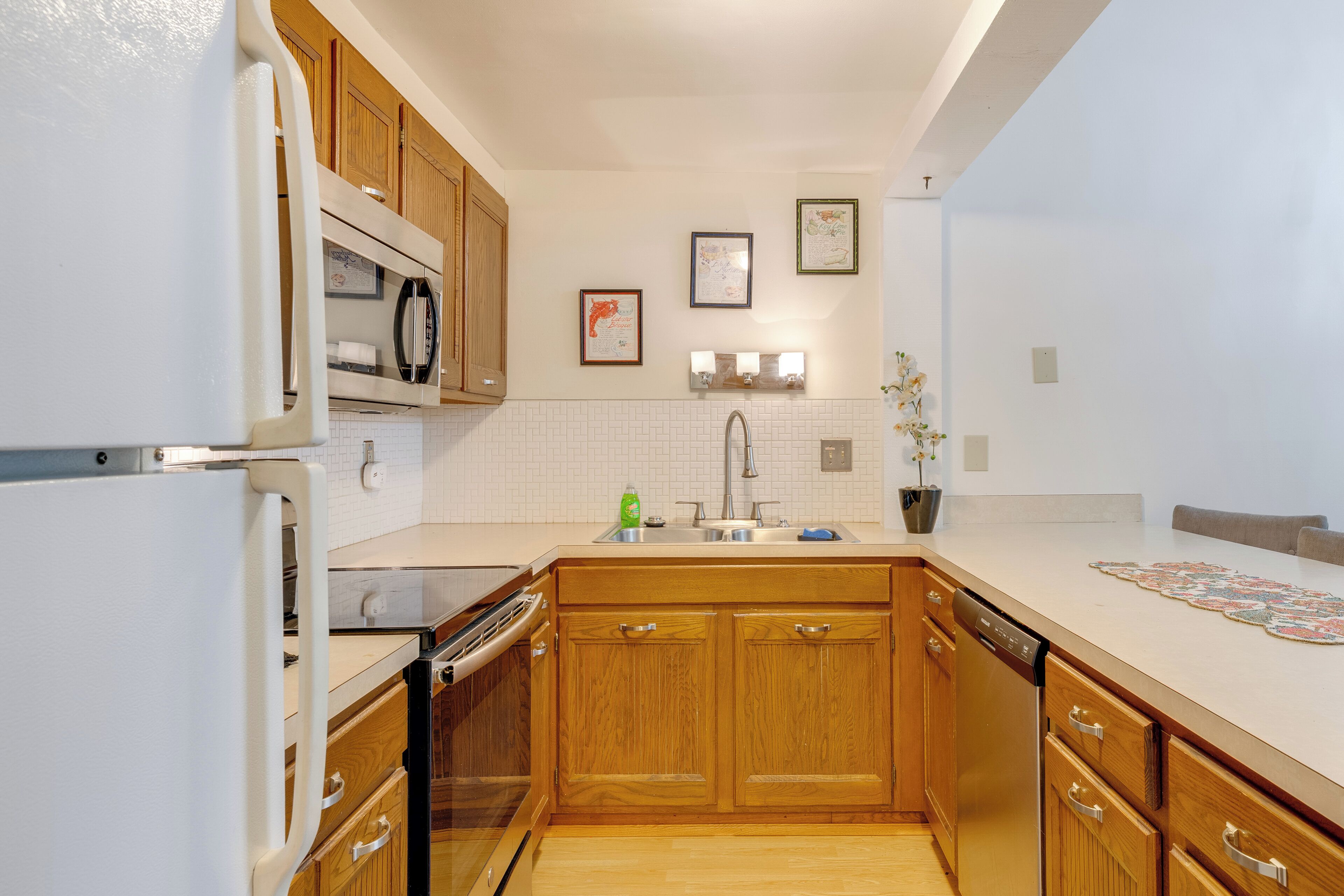 A compact kitchen with wooden cabinets, a built-in oven, and a dishwasher.