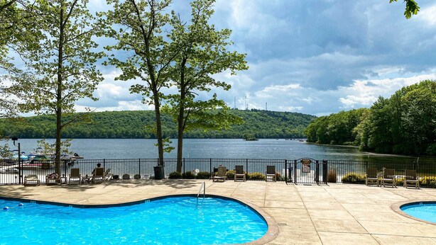 A swimming pool with a view of a lake and trees. - Near Skiing & Lakes: Contemporary Poconos Townhome (Lake Harmony)