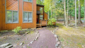 A wooden cabin with a gravel pathway leading to the entrance, surrounded by trees. - Near Skiing & Lakes: Contemporary Poconos Townhome (Lake Harmony)