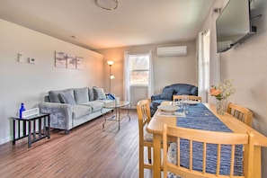 A modern living room with a grey sofa, a dining table with chairs, a small side table, and a floor lamp. - Peaceful Missouri Cabin Rental on 55 Acres! (Canton)