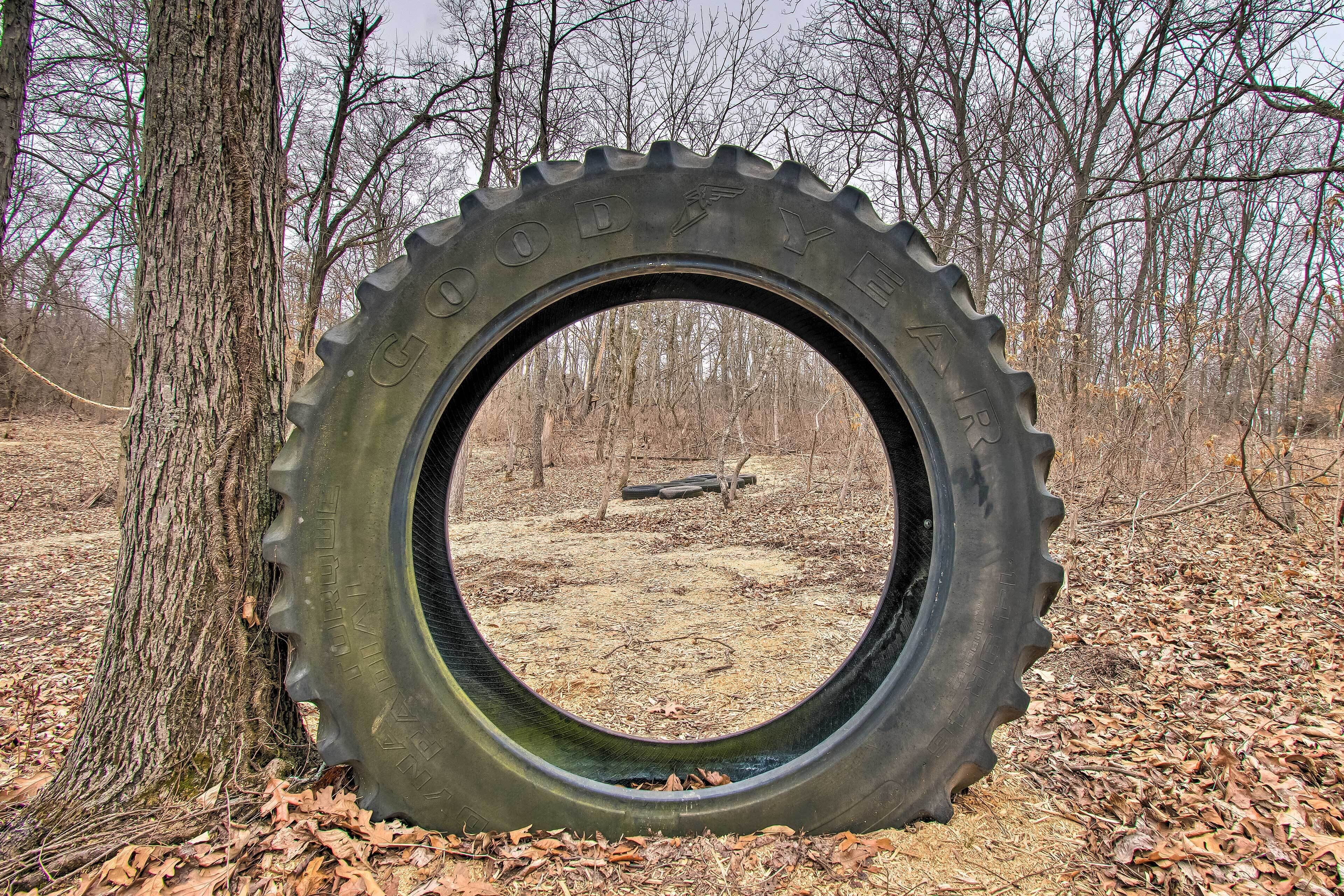 A large tire with the text "GOODYEAR" on it, surrounded by trees and dry leaves.