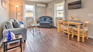 Un salon comprenant un canapé, une table, un téléviseur et un coin repas avec des chaises.