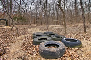 A forest clearing with several discarded tires and a rope swing. - Peaceful Missouri Cabin Rental on 55 Acres! (Canton)