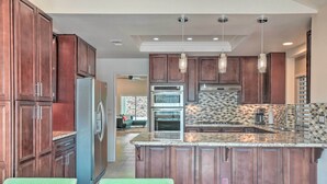 A kitchen with wooden cabinets, a stainless steel refrigerator, and a granite countertop. - Palm Desert Retreat w/ Private Pool, Near Golf! (Palm Desert)