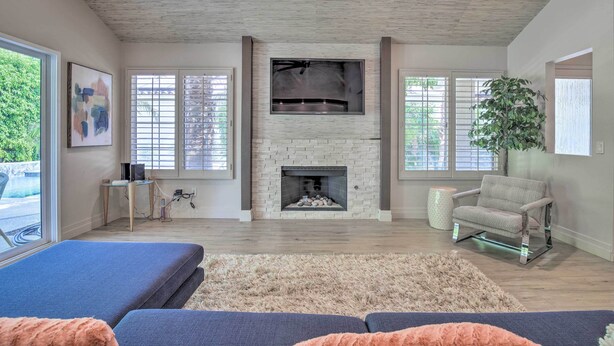A living room with a fireplace, a sofa, a coffee table, and a large plant. - Palm Desert Retreat w/ Private Pool, Near Golf! (Palm Desert)