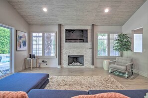 A living room with a fireplace, a sofa, a coffee table, and a large plant.