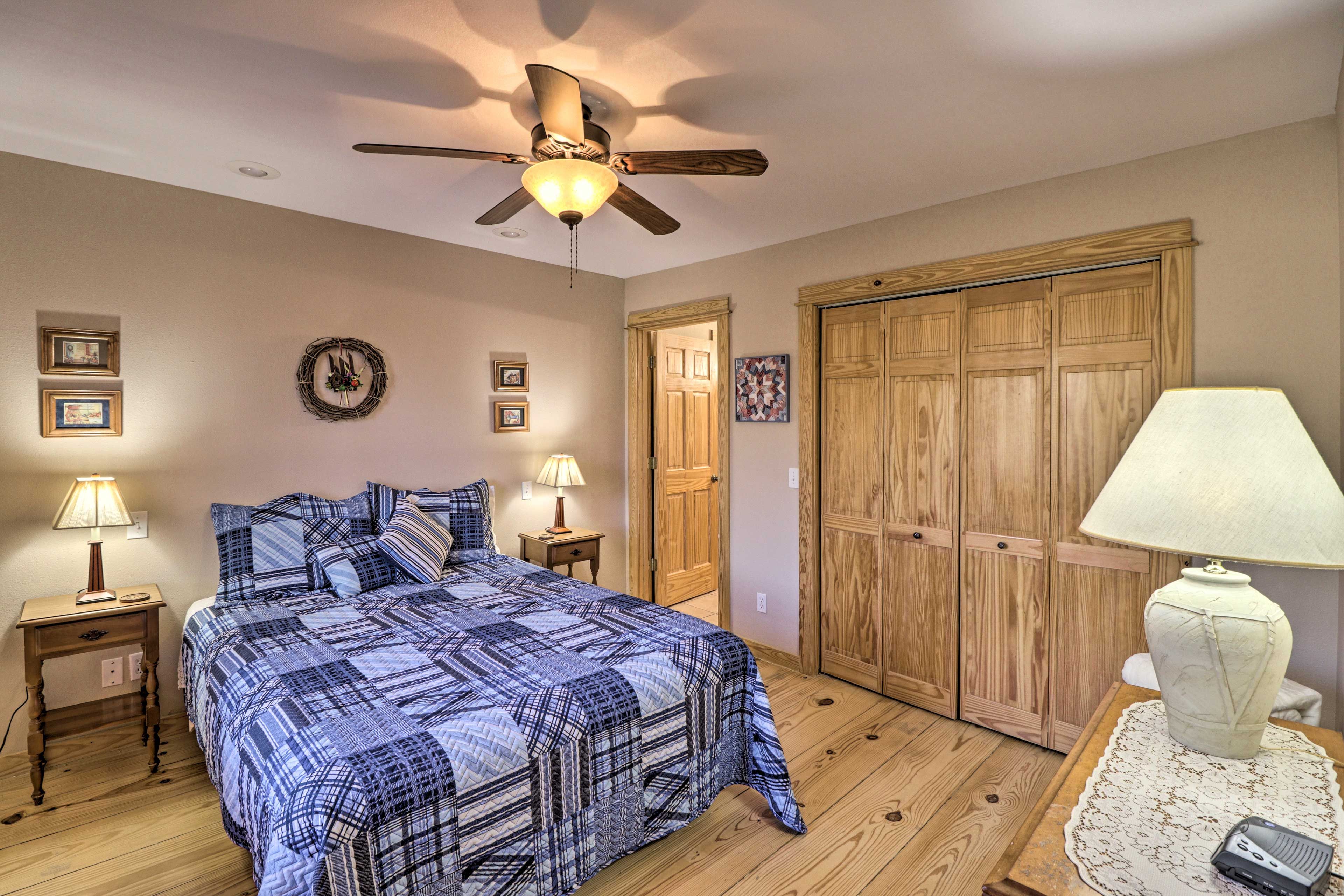 Ein Schlafzimmer mit Bett, Holzboden, Deckenventilator, Holzschrank und Nachttischlampen.