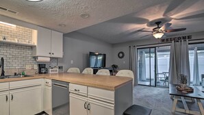 Una cocina moderna con armarios blancos, encimera de madera y ventilador de techo.
