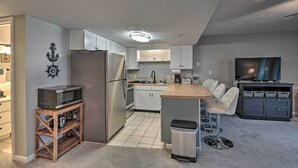 Una cocina moderna con electrodomésticos de acero inoxidable, una isla de madera y piso de baldosas grises.