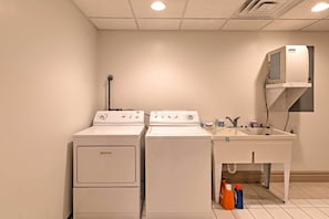 A laundry room with two stacked washers and a sink with cleaning supplies.