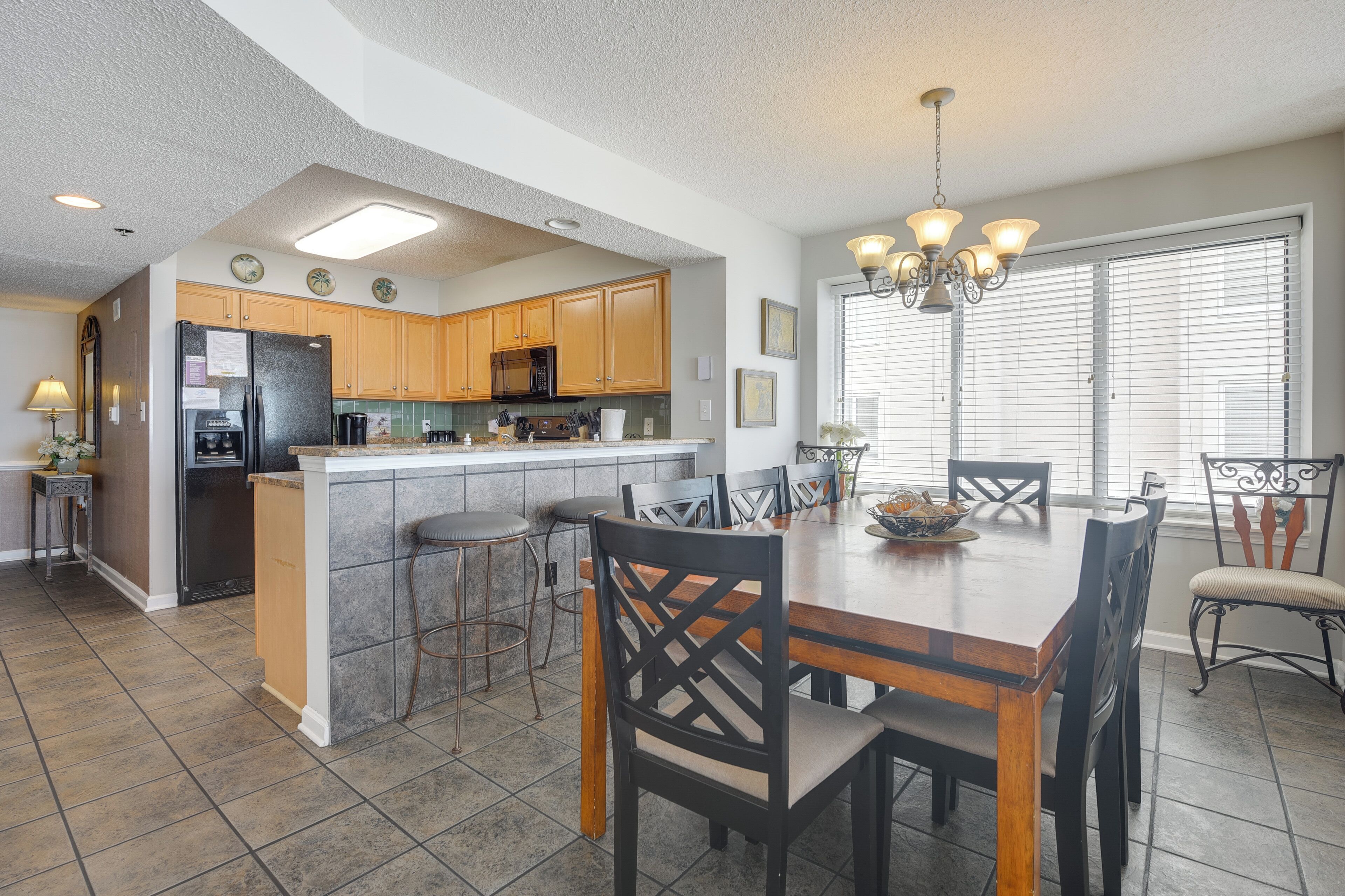 A kitchen with wooden cabinets, a refrigerator, and a dining area with a wooden table and chairs.