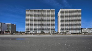A beachfront hotel with multiple high-rise buildings, a sandy beach, and a clear blue sky.