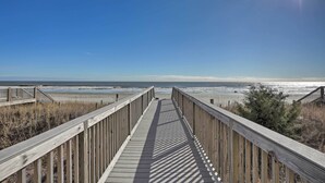 A wooden boardwalk leading to a beach with a clear sky.