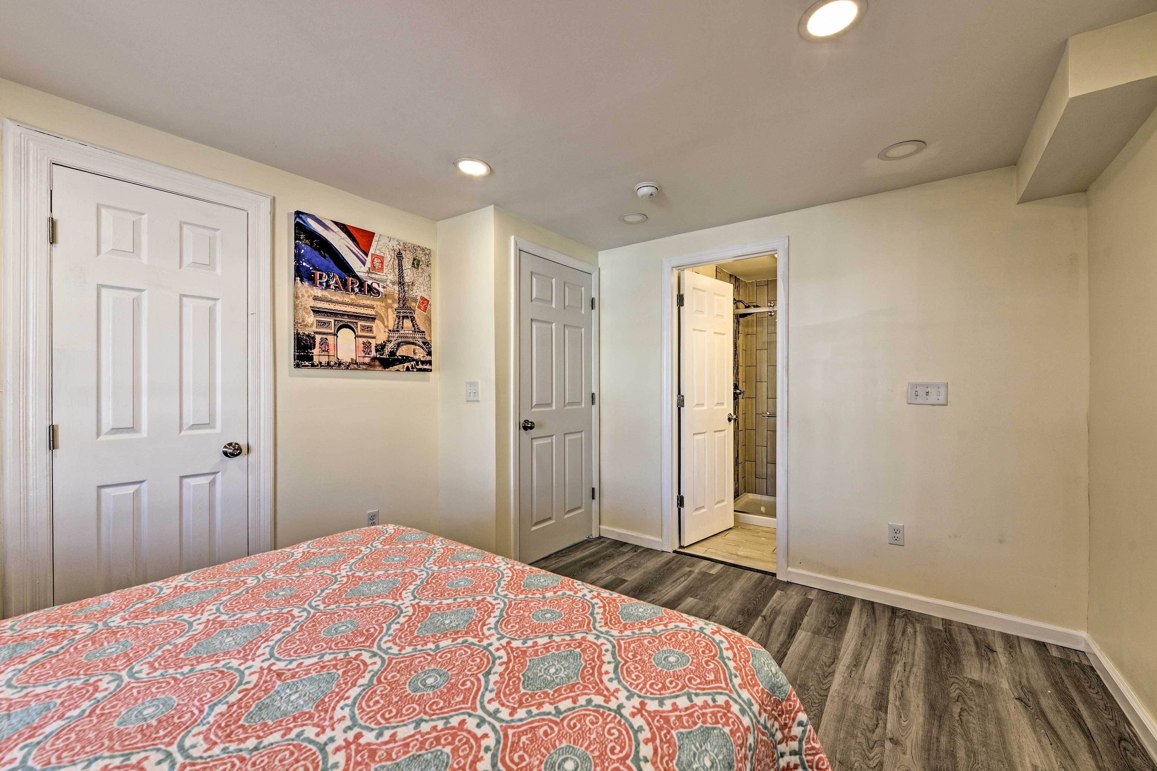 A bedroom with a patterned bedspread, a door with a decorative handle, and a wall-mounted picture of the Eiffel Tower.